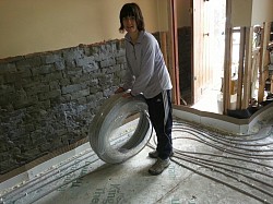 sarah laying pipes underfloor heating, k11/sbr tanked walls in background