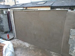 Gates removed from yard opening following house flooding, built solid wall, render and cap . Prevents further flooding