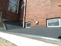 Felted in new black mineral torch felt with drip edges to gutter, edge risers to guide rainfall and felt formed to the wall